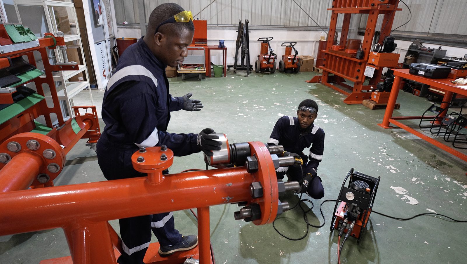 NEZO technicians performing hydraulic bolt-tensioning and tool servicing in the Hi-Force workshop